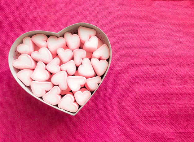 Marshmallow rosa em uma caixa de presente em forma de coração na tela rosa
