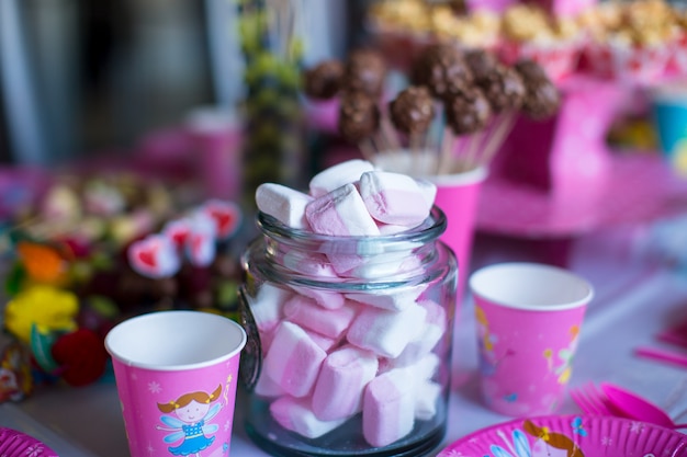 Marshmallow, süß gefärbte Meringues, Popcorn, Puddingkuchen und Cake Pops auf dem Tisch