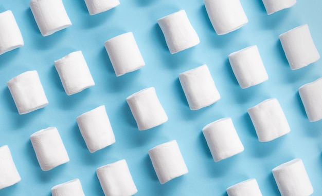 Marshmallows brancos dos doces sobre o fundo azul da tabela.