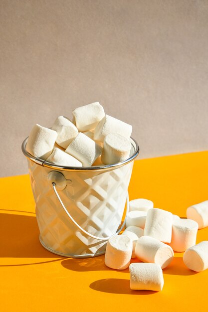 Marshmallows brancos em um balde de metal em um fundo amarelo e cinza moderno um ingrediente