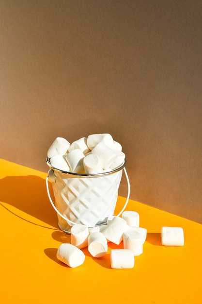 Marshmallows brancos em um balde de metal em um fundo amarelo e cinza moderno um ingrediente