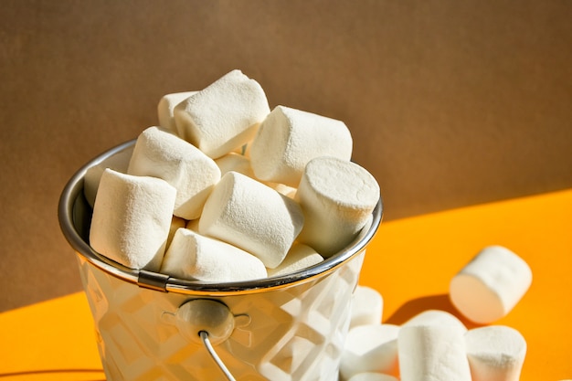 Marshmallows brancos em um balde de metal em um fundo amarelo e cinza moderno um ingrediente