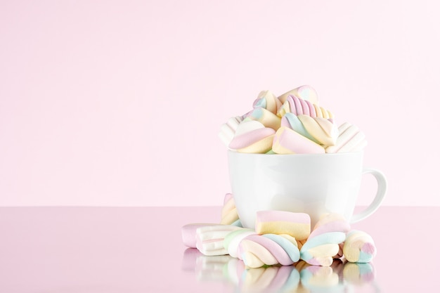 Marshmallows bunte Kaubonbons in einer Tasse auf rosa Hintergrund