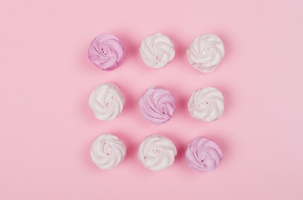 Marshmallows coloridos na mesa-de-rosa. Cor doce zéfiro caseiro ou marshmallow. Postura plana.
