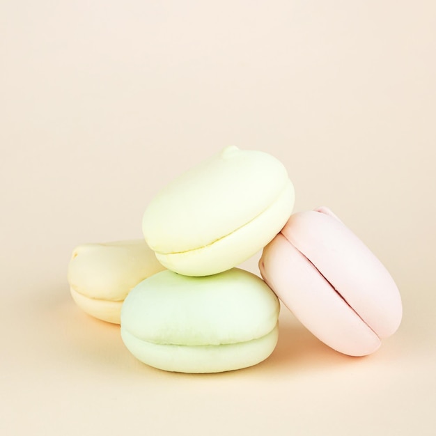 Marshmallows doces e coloridos parecem macarons franceses em fundo creme pastel Macarons coloridos franceses em fileiras