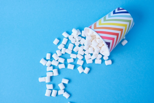 Marshmallows e copos de papel em fundo azul