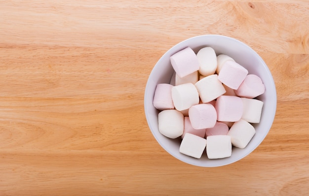 Marshmallows em uma tigela no fundo de madeira