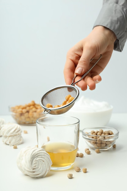 Foto marshmallows grão-de-bico jarro de aquafaba e peneira na mão em fundo branco