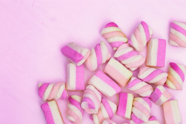 Marshmallows pequenos doces em um fundo rosa