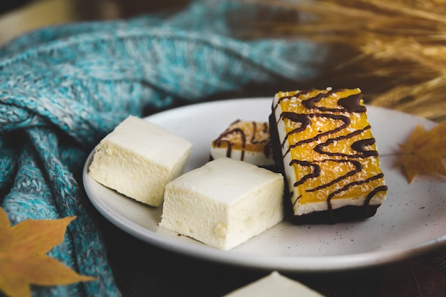 Marshmallows und Orangendessert auf einem weißen Teller.