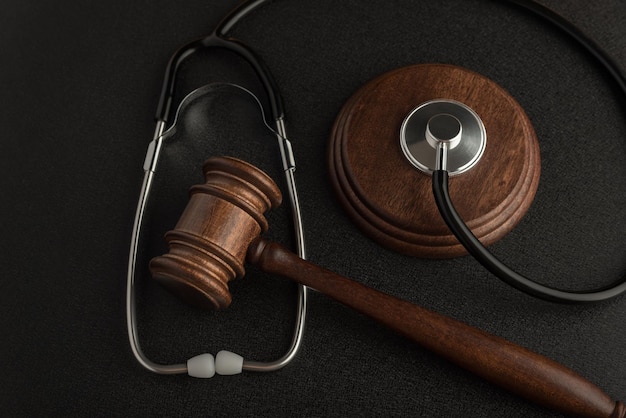 Martelo de martelo de juiz e estetoscópio sobre fundo preto Lei na medicina Sentença por negligência médica