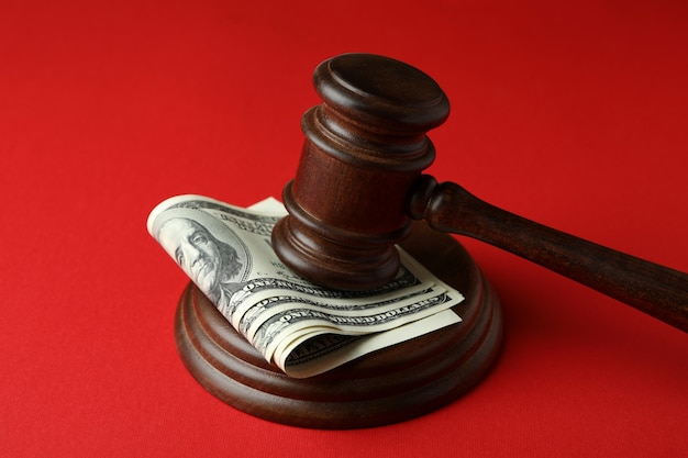 Martelo do juiz com dólares em fundo vermelho