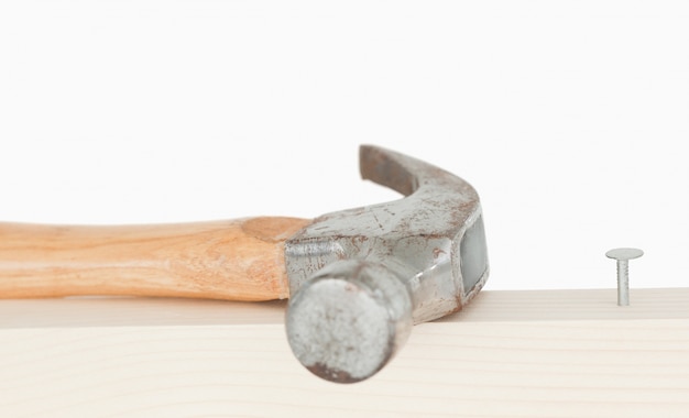 Un martillo y un clavo conducido en una tabla de madera