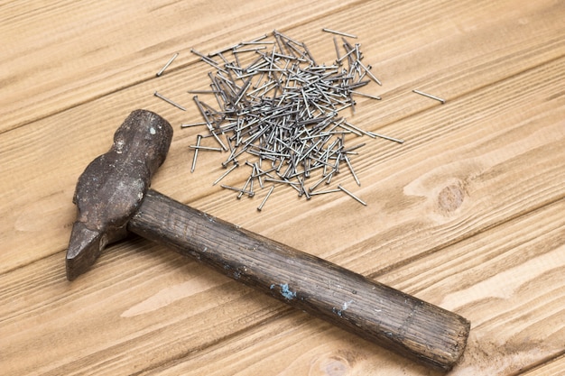 Martillo y clavos sobre fondo claro de madera