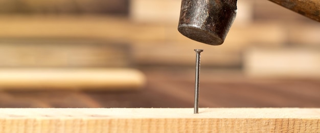 Martillo golpea un primer plano de clavo Martillo martillando un clavo en una tabla de madera