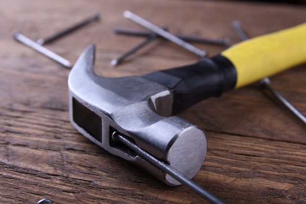 Martillo de hierro, cinta de centímetro y clavos en mesa de madera