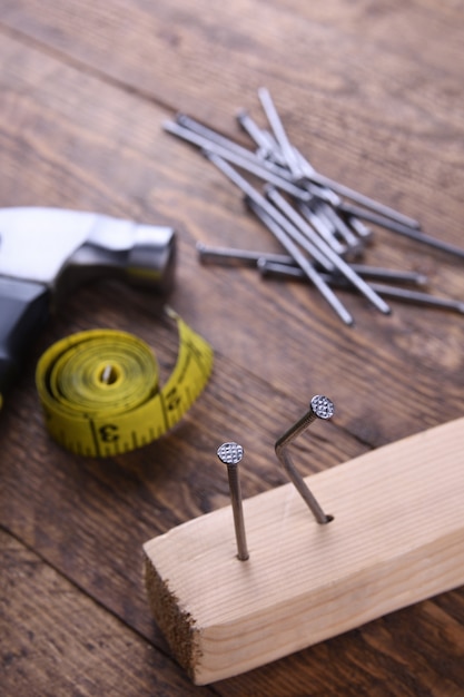 Martillo de hierro, cinta de centímetro y clavos en mesa de madera