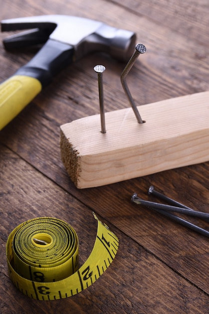 Martillo de hierro, cinta de centímetro y clavos en mesa de madera