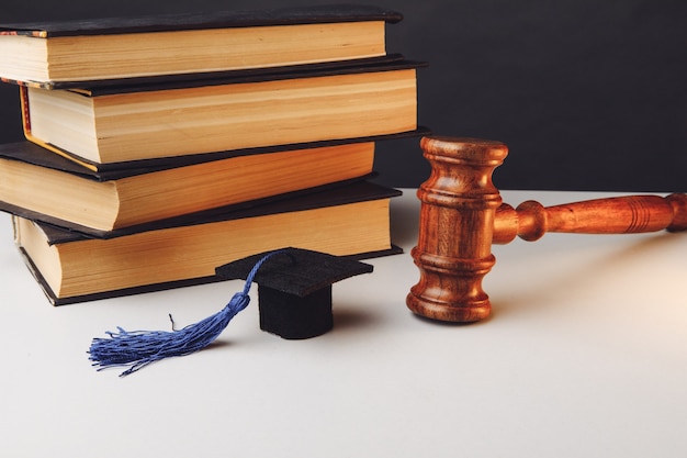 Martillo del juez y gorro de graduación con libros sobre la mesa.