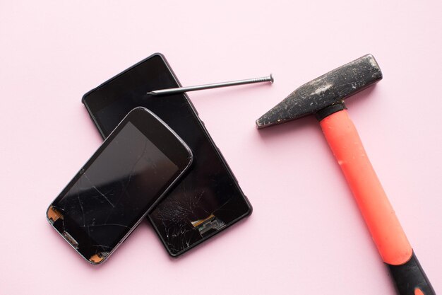 Foto martillo y teléfono móvil con pantalla rota