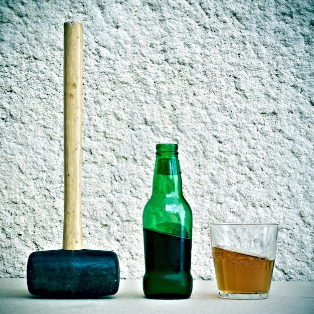 Foto martillo de trineo con botella de cerveza y vaso en la mesa