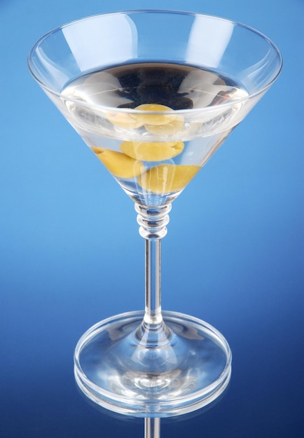 Martini con aceitunas verdes sobre fondo azul.