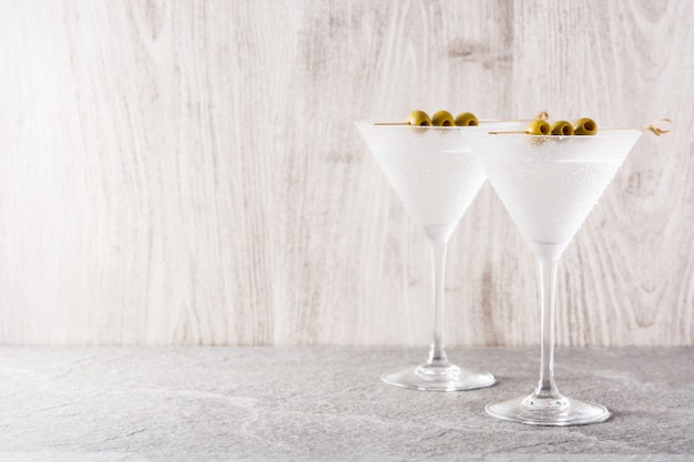 Martini seco clásico con aceitunas en mesa de piedra gris