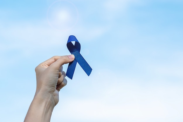 Foto marzo mes de concientización sobre el cáncer colorrectal, mujer sosteniendo un lazo azul oscuro para apoyar a las personas que viven y padecen enfermedades