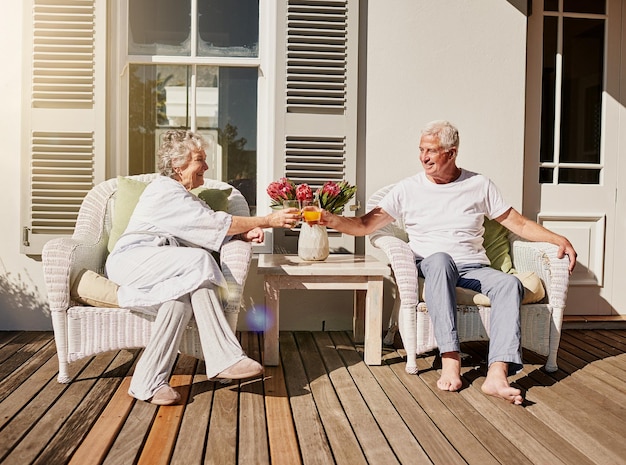 Por más mañanas como esta Fotografía de una feliz pareja de ancianos brindando con jugo en el patio de su casa