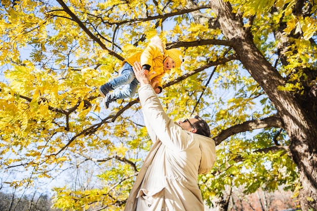 Foto más, más, papá, eso es divertido. un joven padre feliz lanza a su lindo y feliz bebé en el aire.