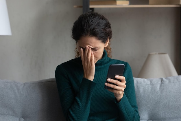 más notícias no ecrã confusa frustrada jovem senhora latina cobrir o rosto com a palma virar-se para longe do celular vendo chamada importante perdida mulher millennial desesperada receber mensagem no telefone sobre demissão do emprego