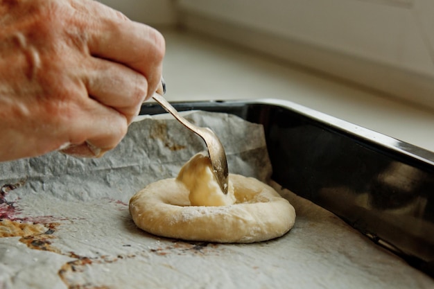 Foto la masa amasada cruda se encuentra en el suelo la mano de la mujer vierte queso cottage con una cuchara en la masa cocina horneado