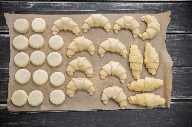 Masa cruda en los croissants y galletas de papel para hornear