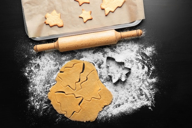 Masa cruda y galletas navideñas en la mesa