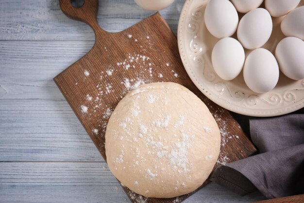 Masa cruda y plato con huevos en la mesa de la cocina