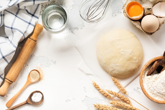 Masa e ingredientes para la preparación de pasta, masa, huevos, harina, agua y sal sobre una mesa vieja rústica ligera