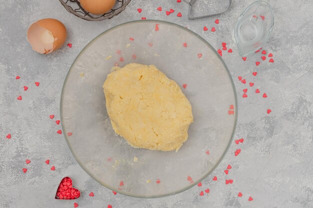 La masa está lista para la preparación de galletas en forma de corazón con esmaltes de chocolate rosado para el Día de San Valentín