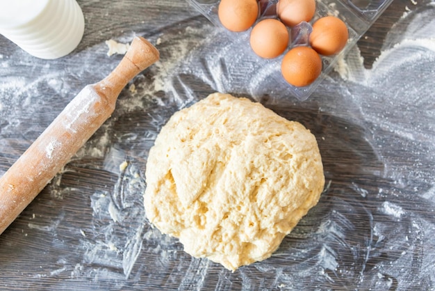 La masa fresca en bruto en una superficie de madera enmohecida y los ingredientes para la fabricación de la masa