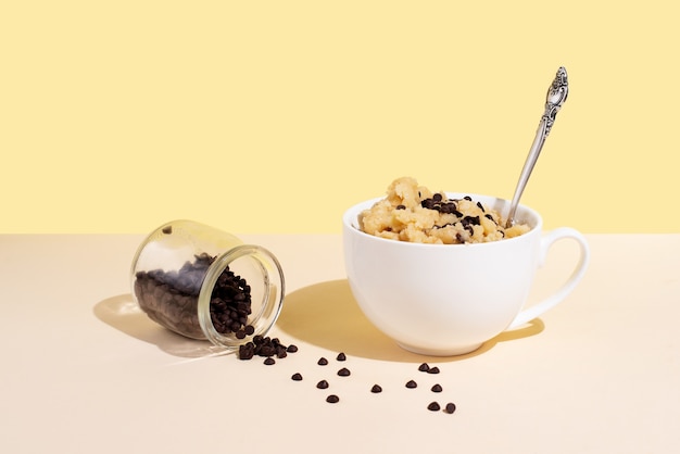 Masa de galleta comestible en taza blanca con chispas de chocolate y cuchara