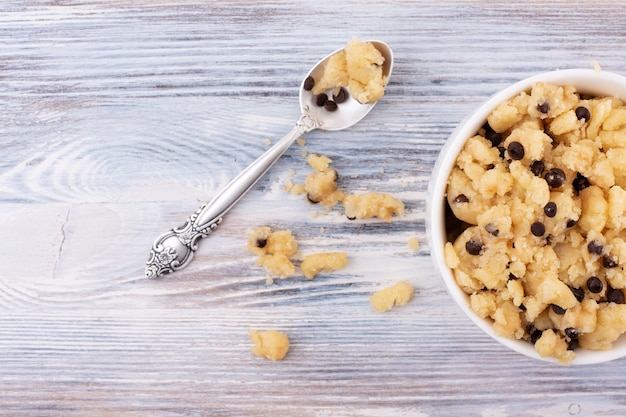 Masa de galleta comestible en una taza con la cuchara y las migas