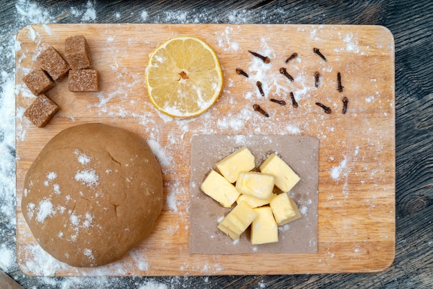 Foto masa para galletas en la mesa de la cocina. ingredientes - mantequilla, limón, harina, azúcar, clavo.