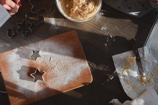 Masa de mantequilla para galletas de jengibre enrollada sobre la tabla de madera. Cortar galletas en forma de estrella.