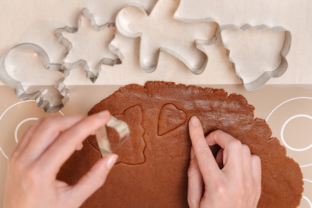 Masa de pan de jengibre con diferentes formas de cortadores de metal para galletas familiares navideñas con jengibre
