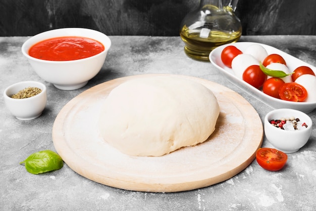 Masa de pizza e ingredientes para pizza en espacio gris