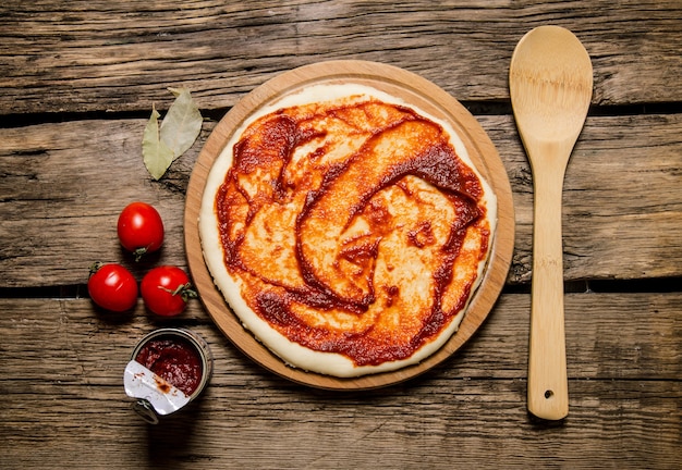 La masa de pizza enrollada con pasta de tomate y tomates.
