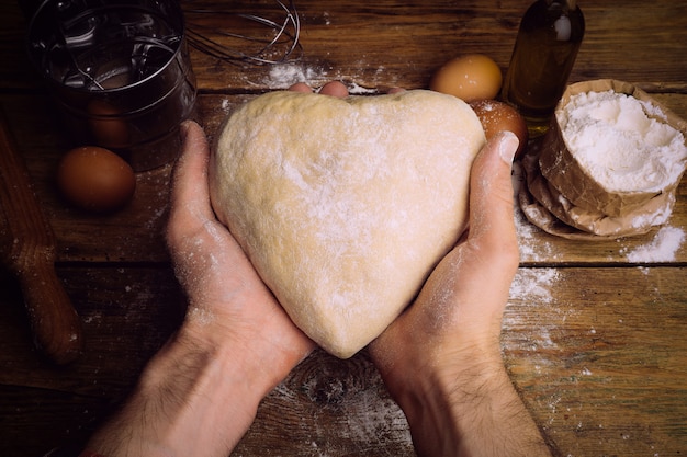 Masa de pizza que cocina en la cocina casera. Masa casera para pan, pizza, bollería y bollos. Ingredientes de masa sobre un fondo rústico de madera