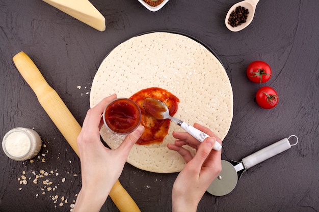 Masa de pizza, salsa de tomate se aplican con las manos a la masa.