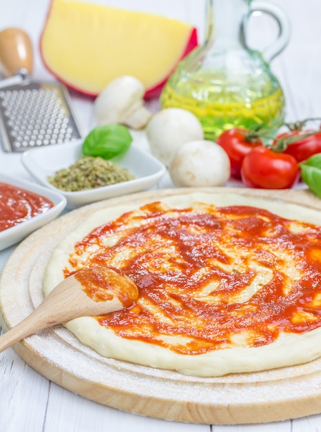 Masa de pizza con salsa de tomate sobre una tabla de madera