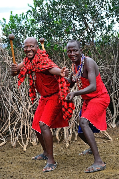 MASAI MARA, KENYA - 13 de agosto: guerreros Masai bailando saltos tradicionales como ceremonia cultural. Así como las mujeres cantan y bailan. Parque Nacional de Masai Mara, 13 de agosto de 2015 en Kenia