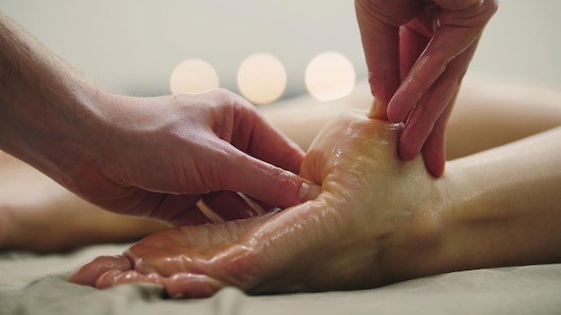 Masaje con aceite para el talón en la pierna Tratamiento de relajación para mujeres jóvenes